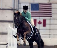 girl and horse jumping over fence